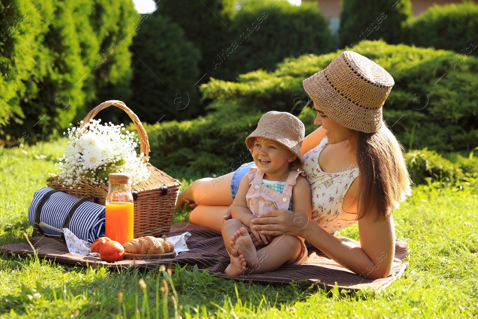 Photo of Mother with her baby daughter having picnic in garden on sunny day