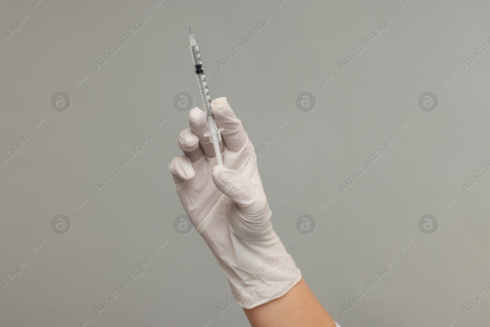 Photo of Doctor holding medical syringe on grey background, closeup