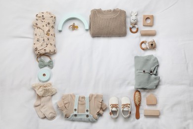 Photo of Layout with baby outfit and cute accessories on white bed, top view. space for text