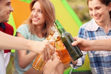 Photo of Group of young people drinking beer near camping tent, outdoors