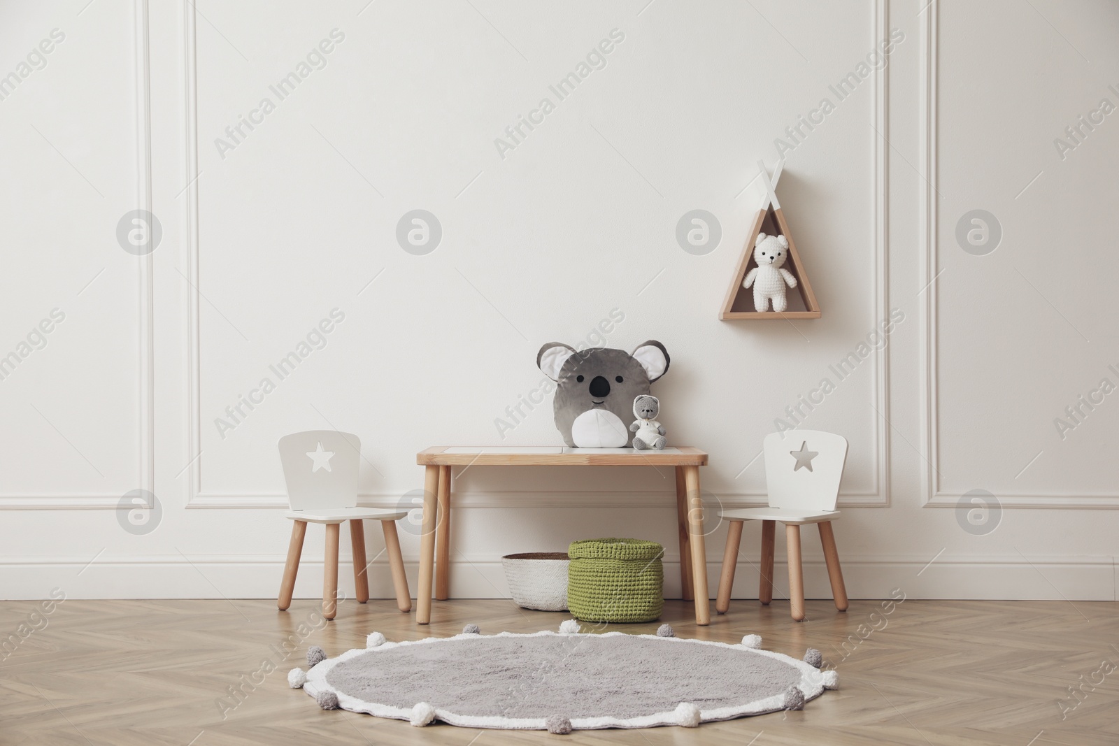 Photo of Cute child room interior with furniture, toys and wigwam shaped shelf on white wall