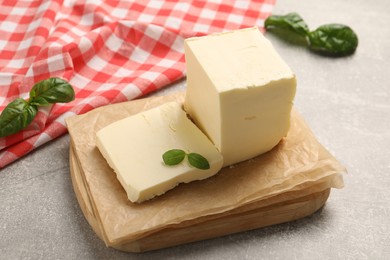 Photo of Block of tasty butter with basil on grey table