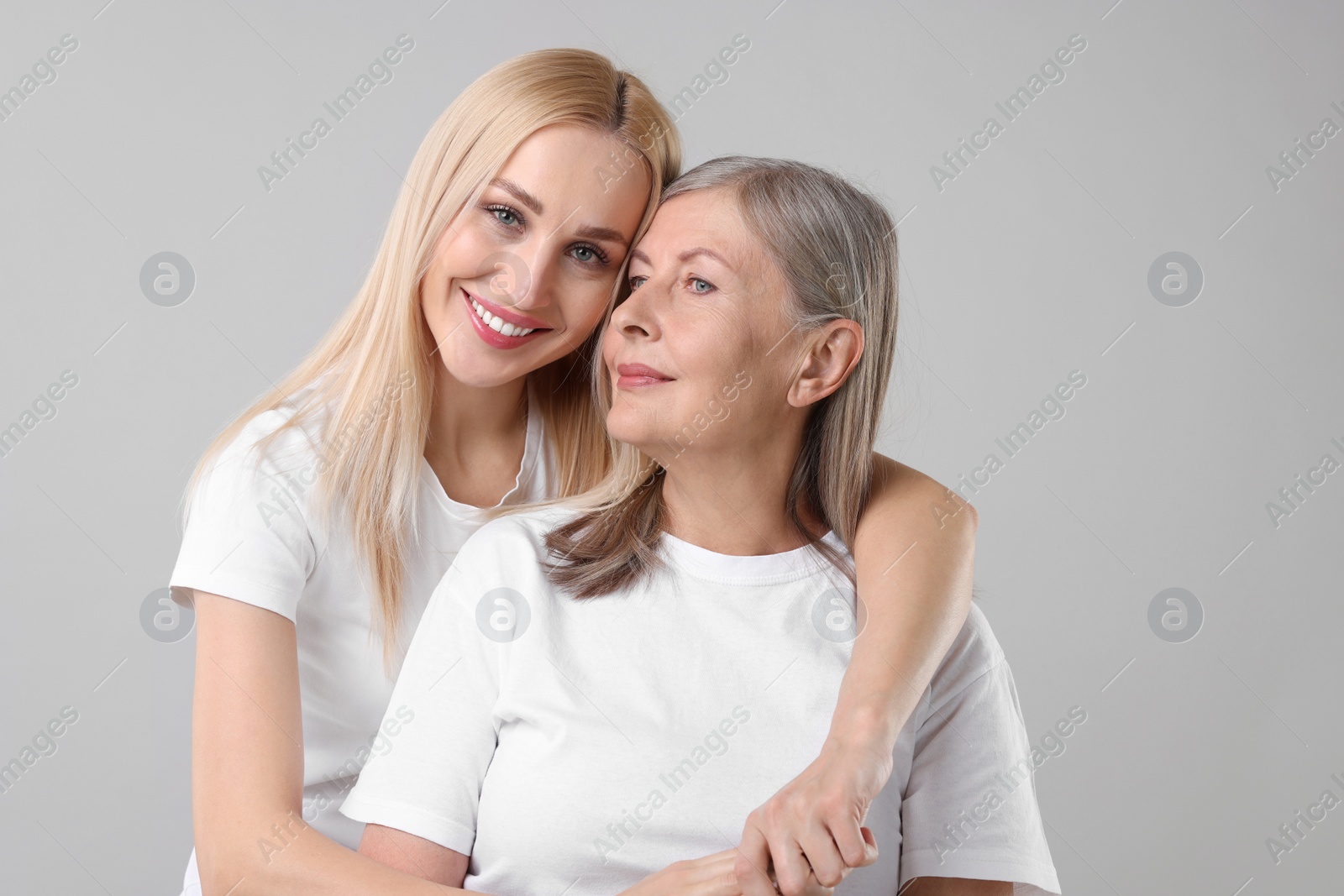 Photo of Family portrait of young woman and her mother on light grey background