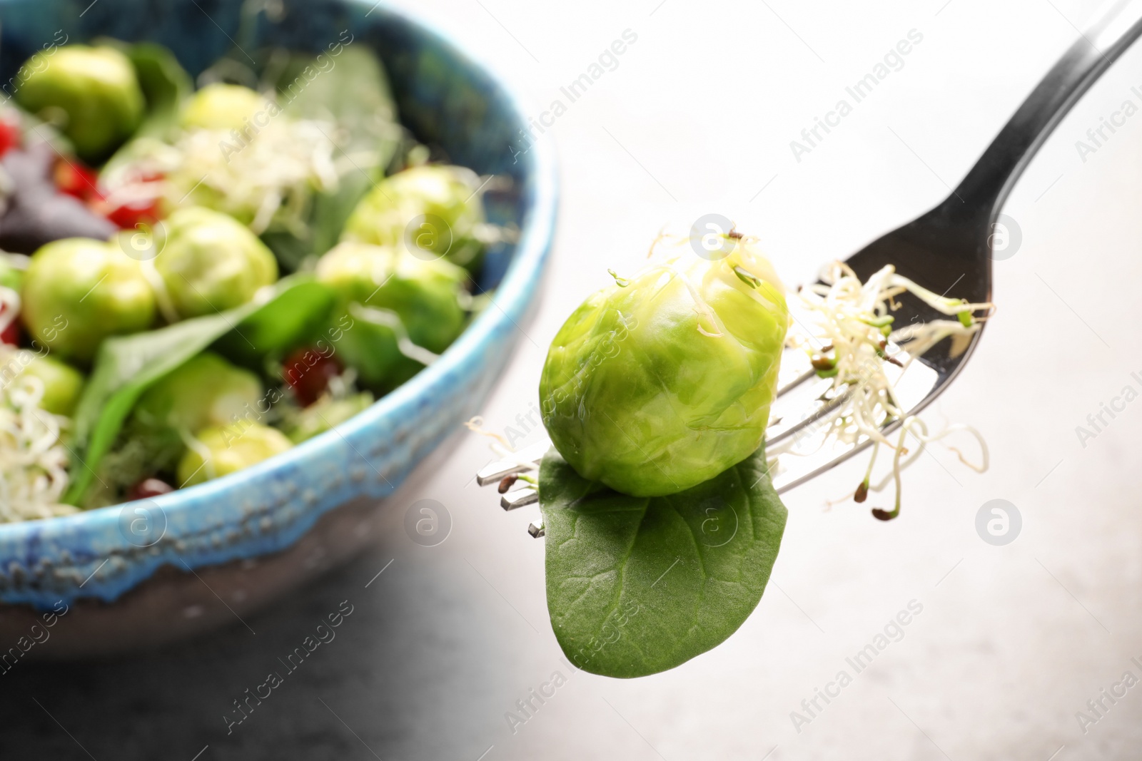 Photo of Fork with delicious Brussels sprouts salad over table, closeup