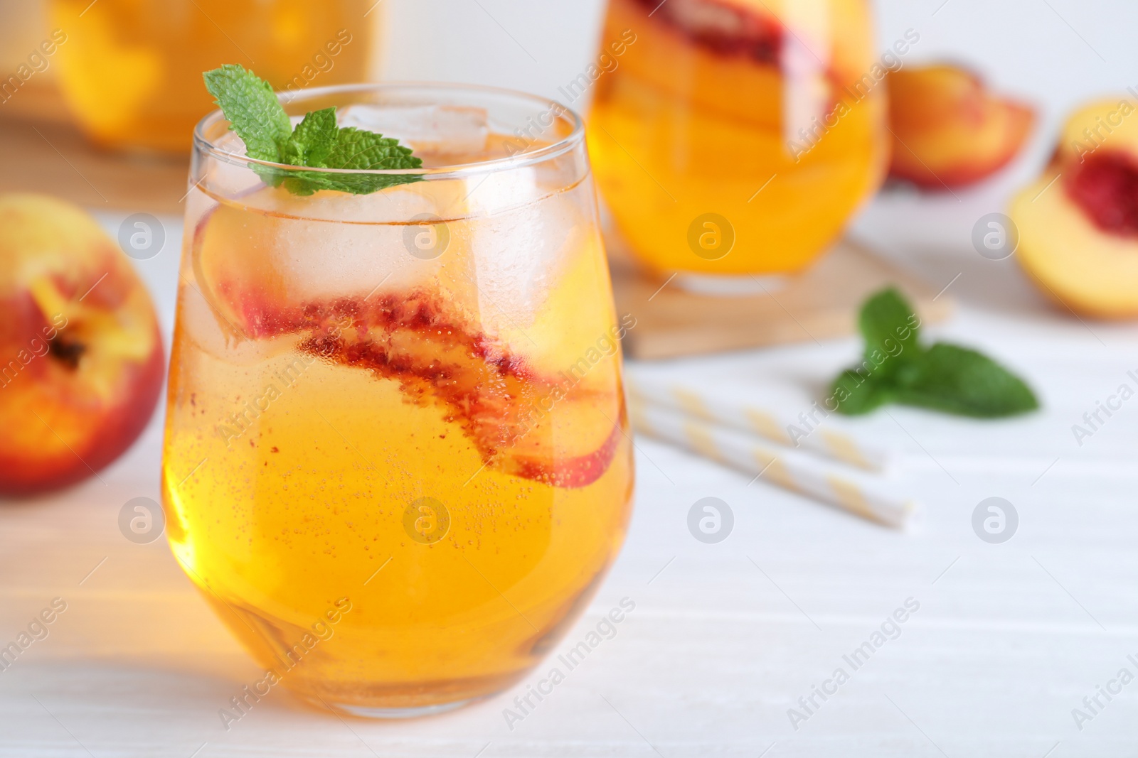 Photo of Delicious peach lemonade made with soda water on white wooden table, closeup. Space for text