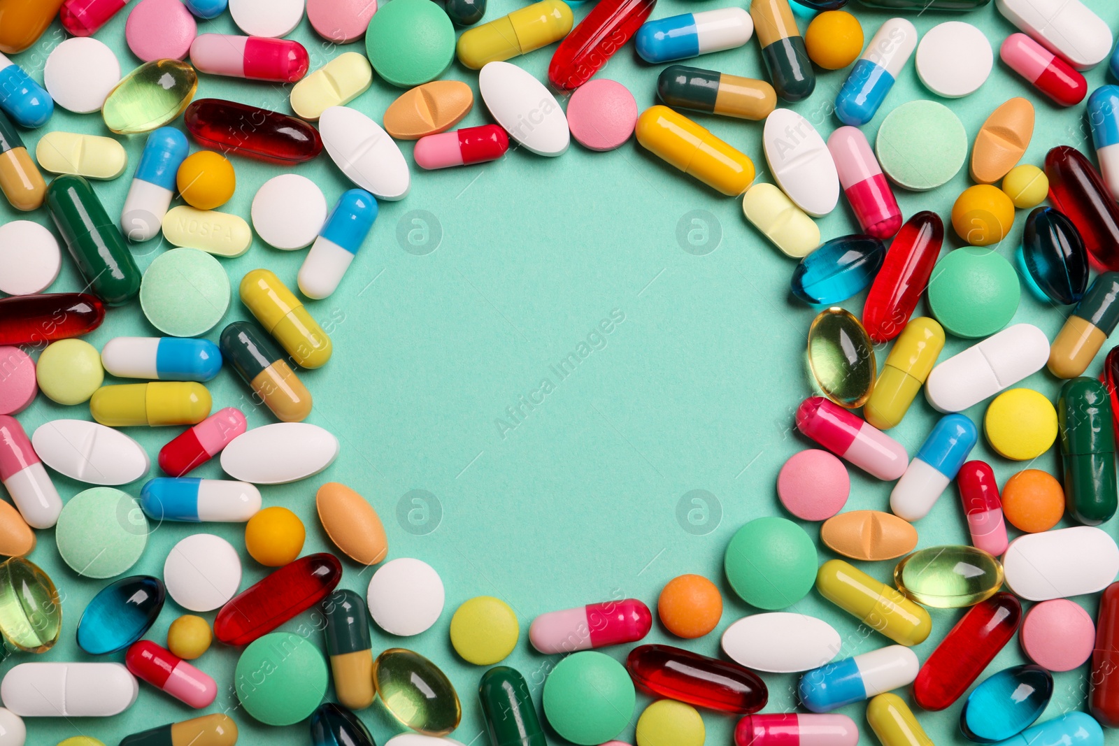 Photo of Frame made of many different pills on turquoise background, flat lay. Space for text