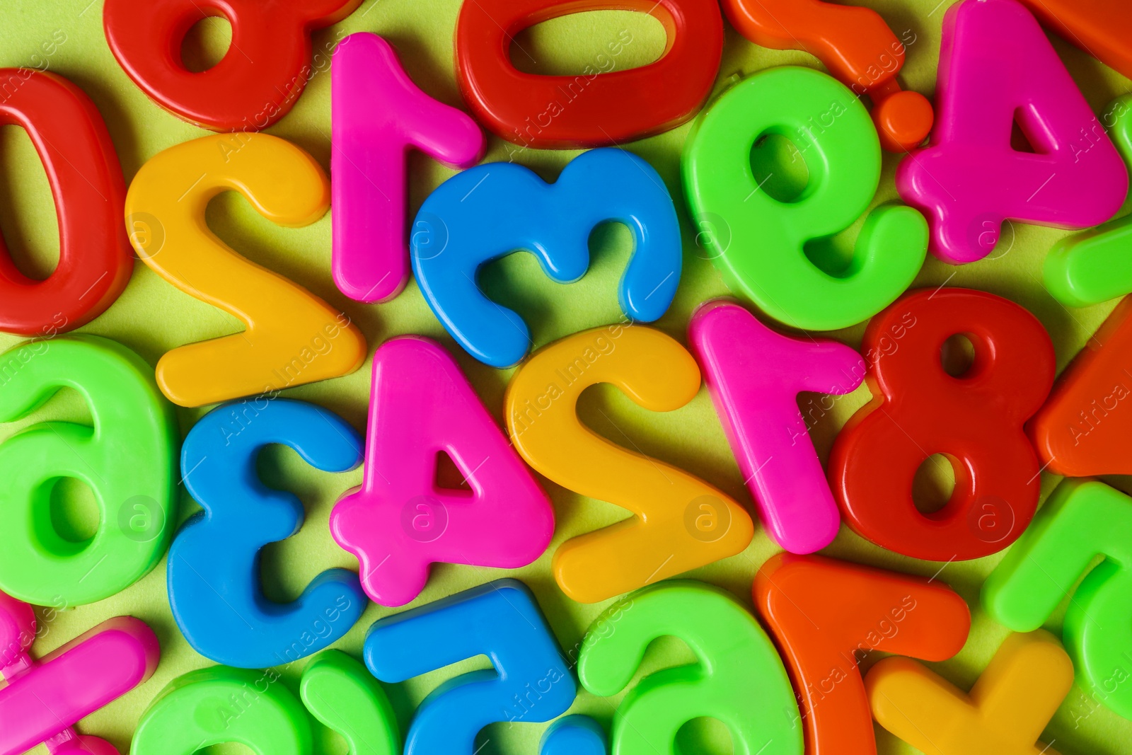 Photo of Colorful magnetic numbers on light green background, flat lay