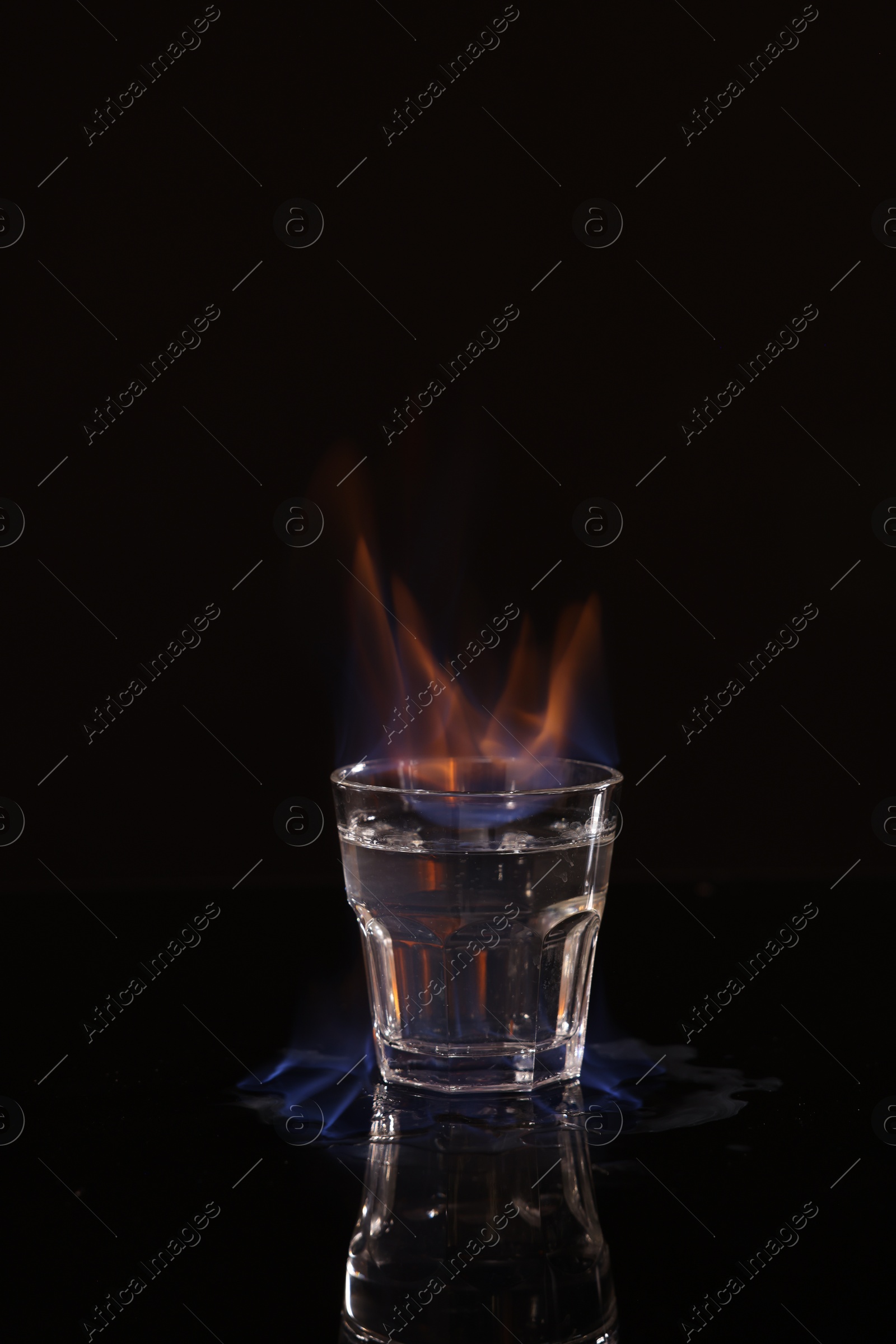 Photo of Flaming vodka in shot glass on black background