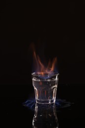 Photo of Flaming vodka in shot glass on black background