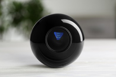 Magic eight ball with prediction Can't Say Now on light table, closeup