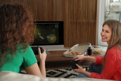 Photo of Young women playing video games at home