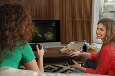 Young women playing video games at home