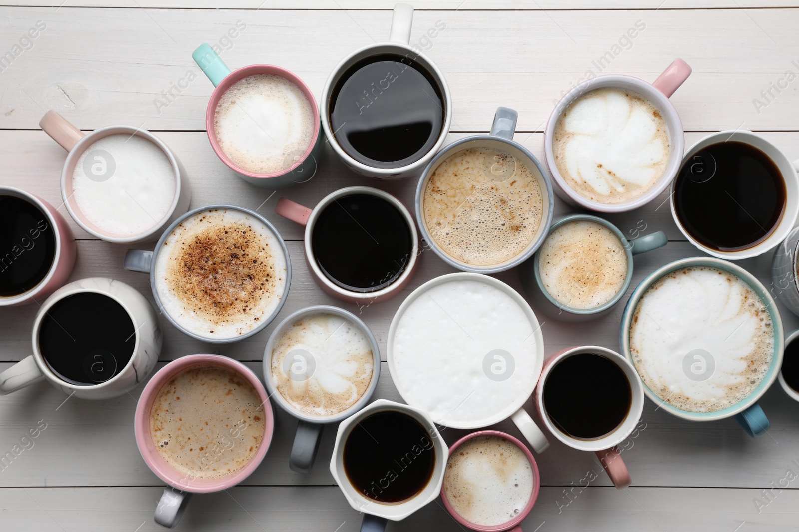 Photo of Many different cups with aromatic hot coffee on white wooden table, flat lay