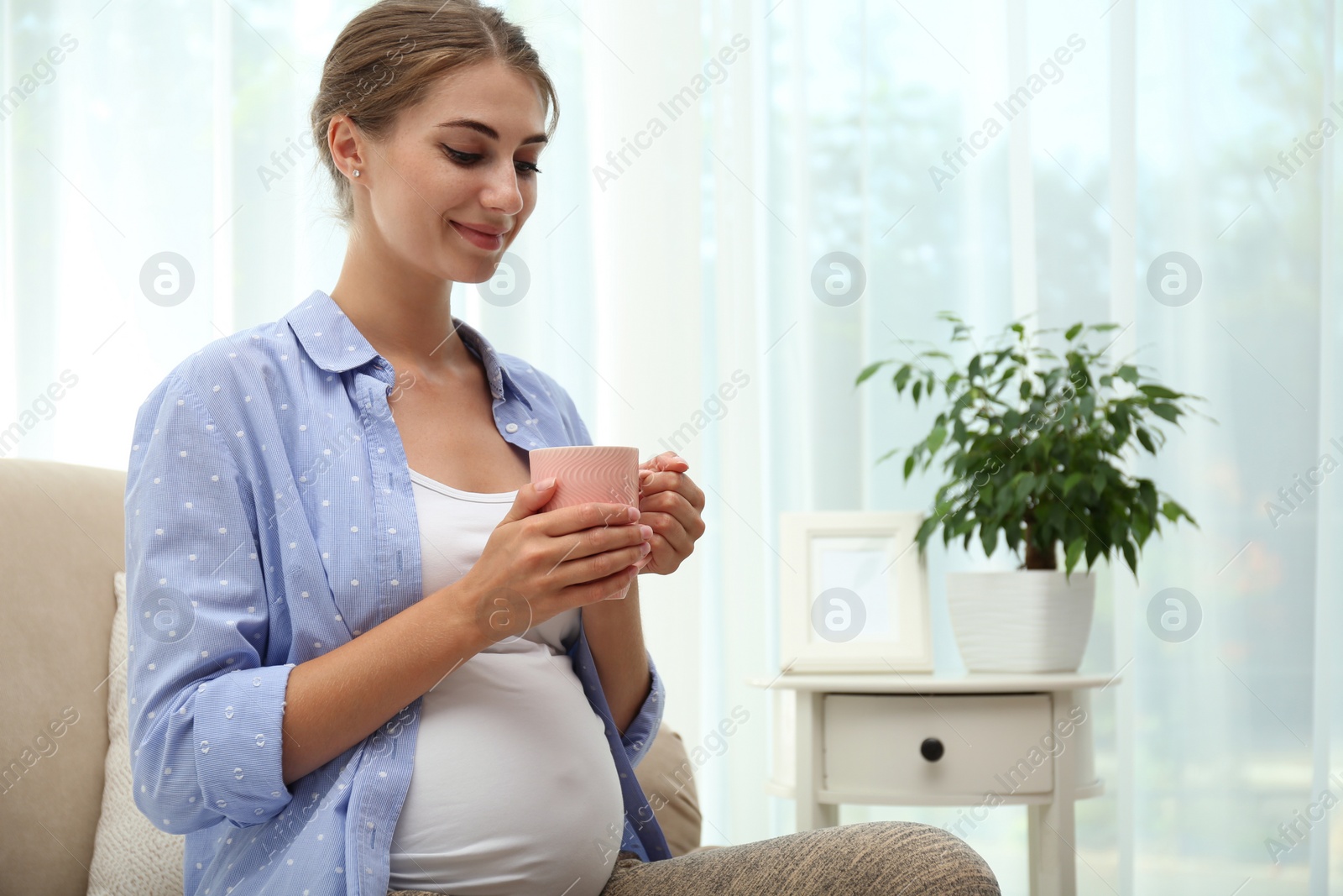 Photo of Happy pregnant woman drinking tea at home