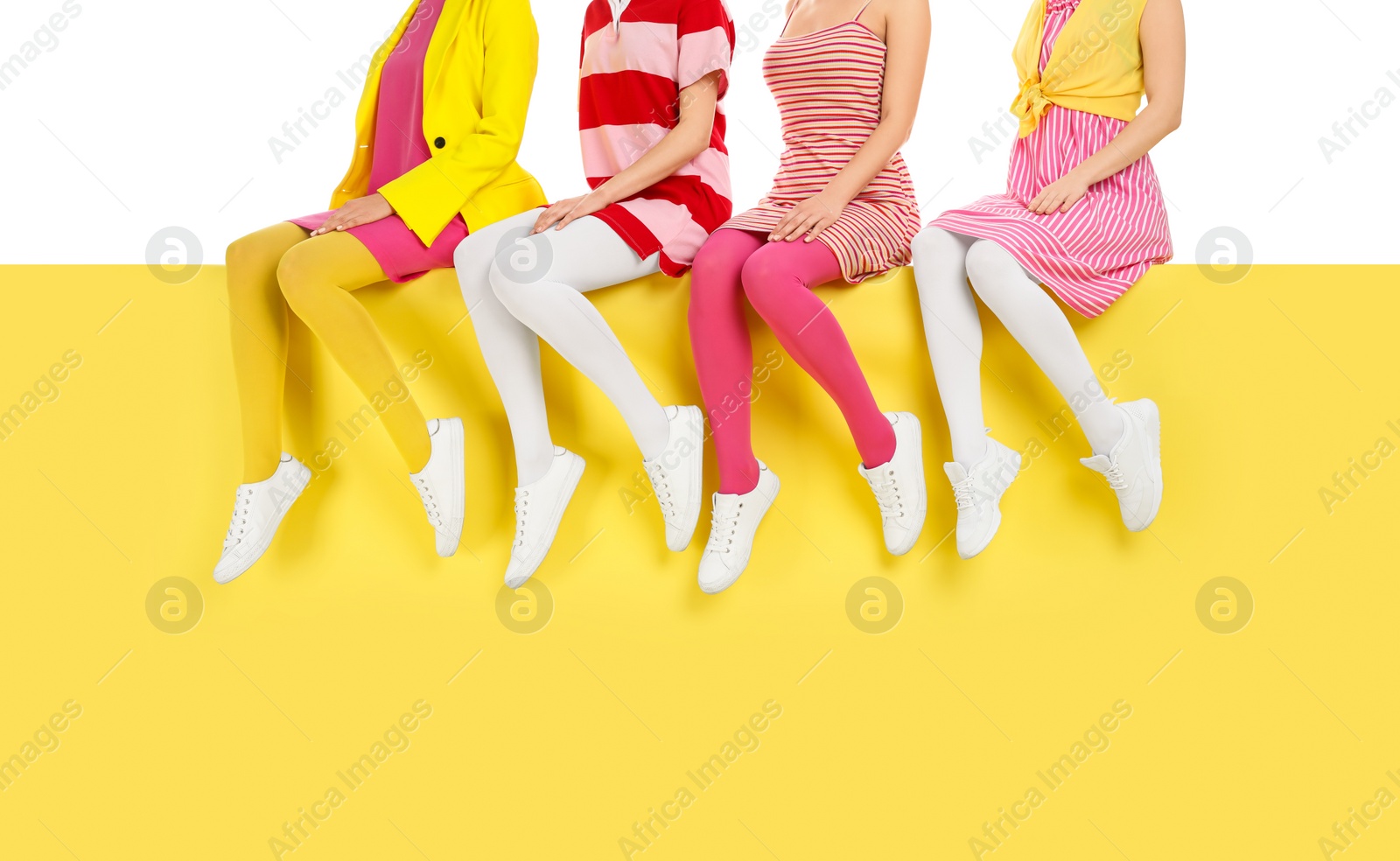 Photo of Women wearing bright tights sitting on color background, closeup