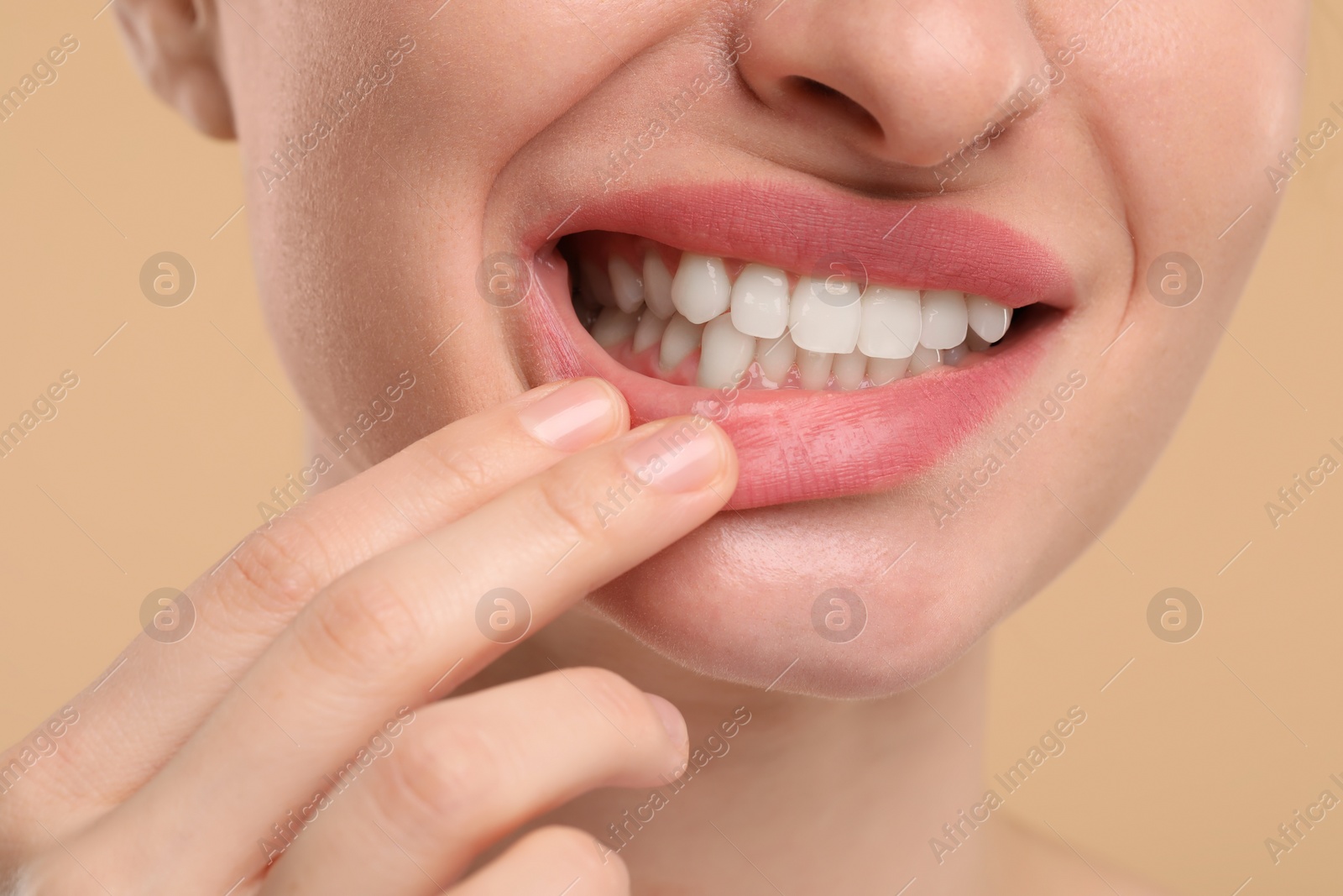 Photo of Woman showing her clean teeth on beige background, closeup