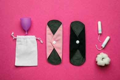 Photo of Reusable cloth pads and menstrual cup near disposable tampons on pink background, flat lay