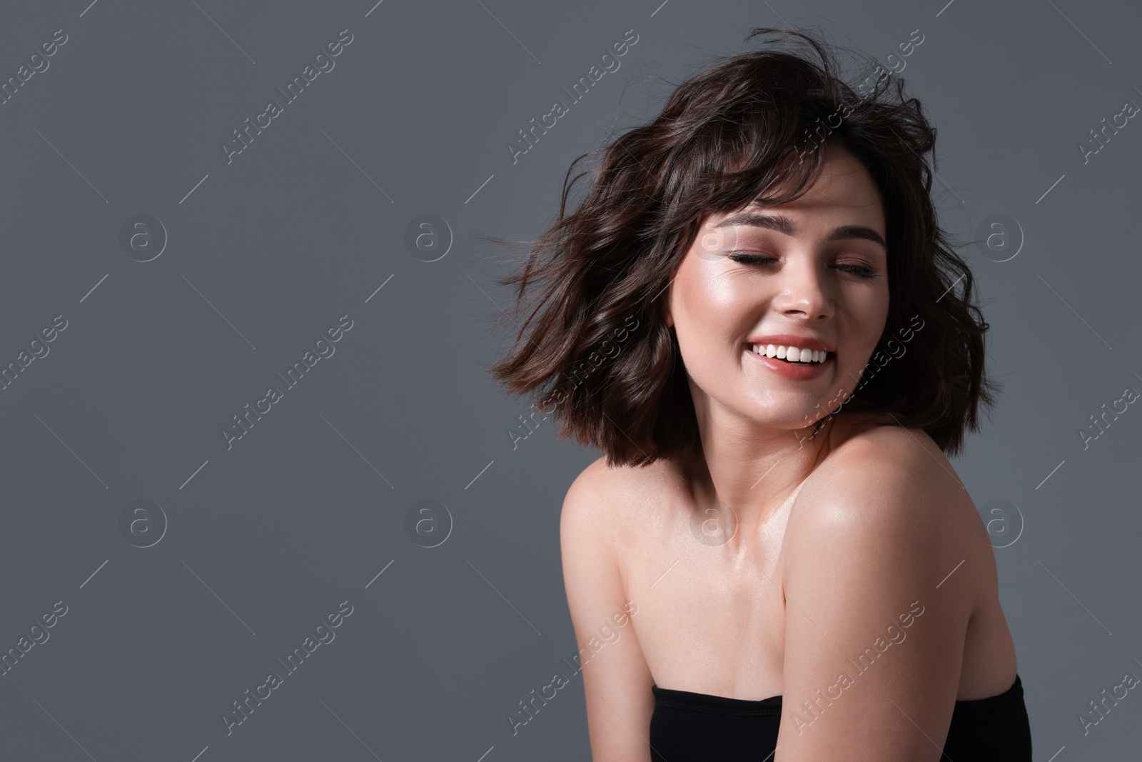 Photo of Portrait of beautiful young woman with wavy hairstyle on grey background. Space for text