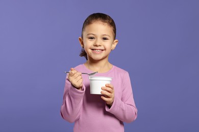 Photo of Girl with tasty yogurt on violet background