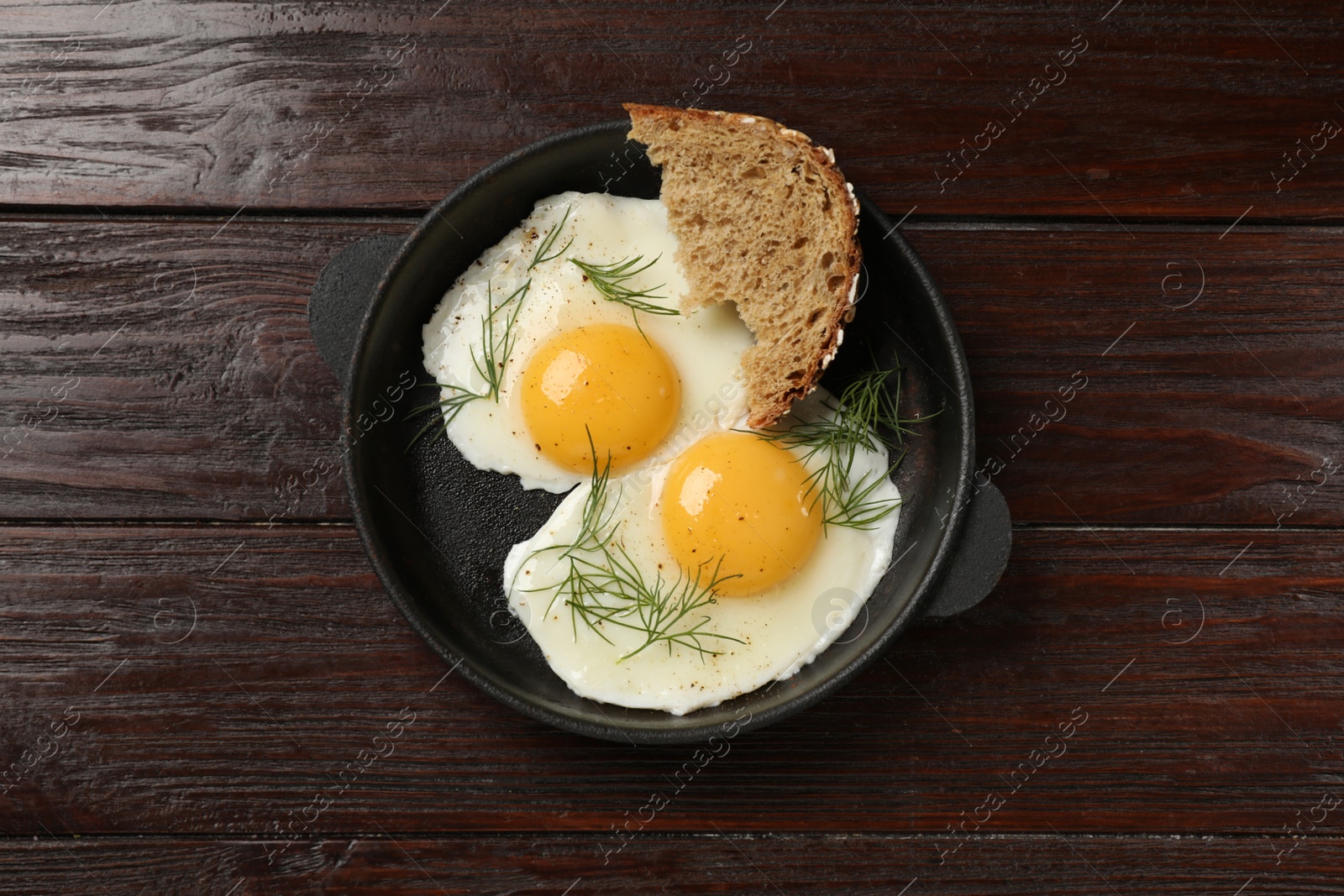 Photo of Delicious fried eggs served with bread on wooden table, top view