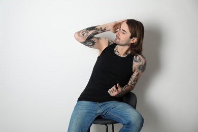 Young man with tattoos on body against white background