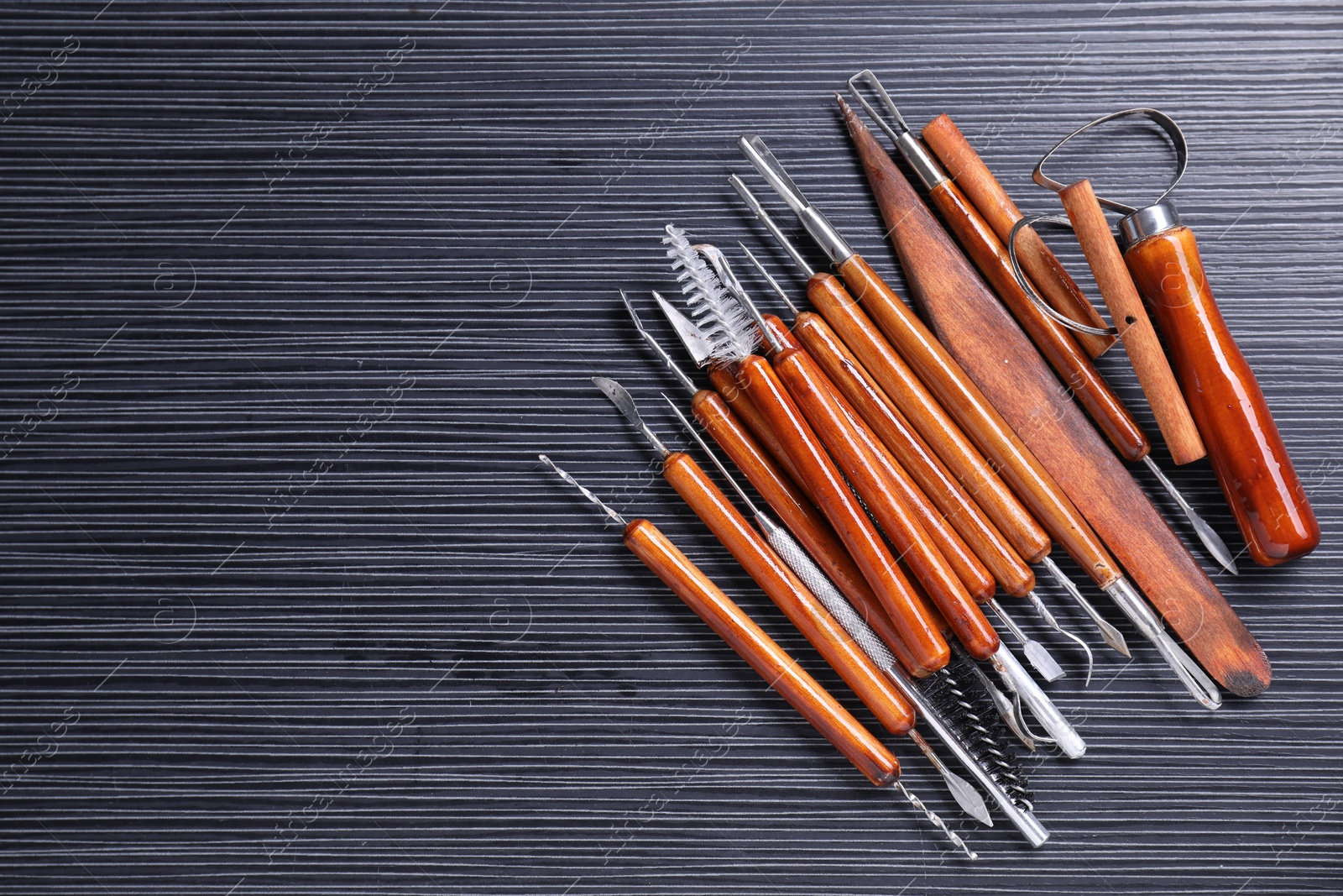 Photo of Set of clay crafting tools on black table, flat lay. Space for text