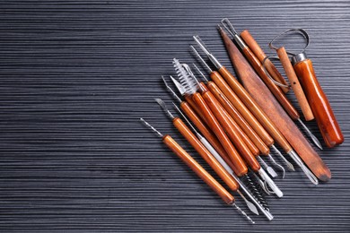 Photo of Set of clay crafting tools on black table, flat lay. Space for text