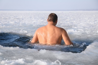 Photo of MYKOLAIV, UKRAINE - JANUARY 06, 2021: Man immersing in icy water on winter day, back view