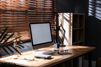 Photo of Modern computer and stationery on wooden table in office