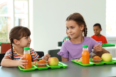 Children sitting at table and eating healthy food during break at school