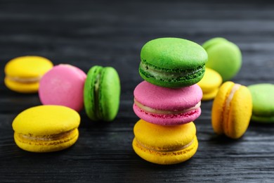 Photo of Many colorful macarons on black wooden table