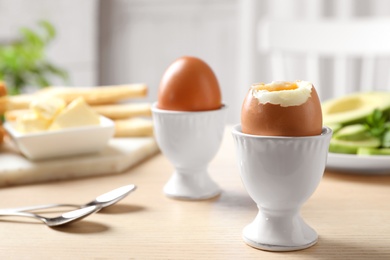 Photo of Cups with soft boiled eggs on wooden table, space for text. Healthy breakfast