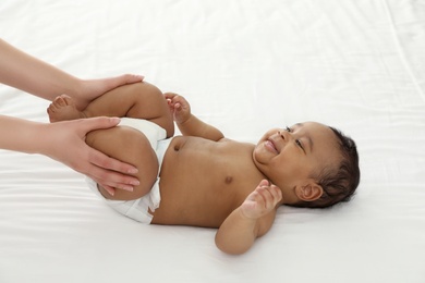 Photo of Mother and her cute child on white bed. Baby massage and exercises