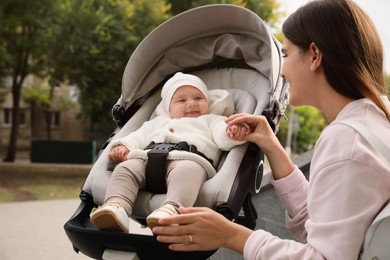 Photo of Young mother with her adorable baby in stroller outdoors