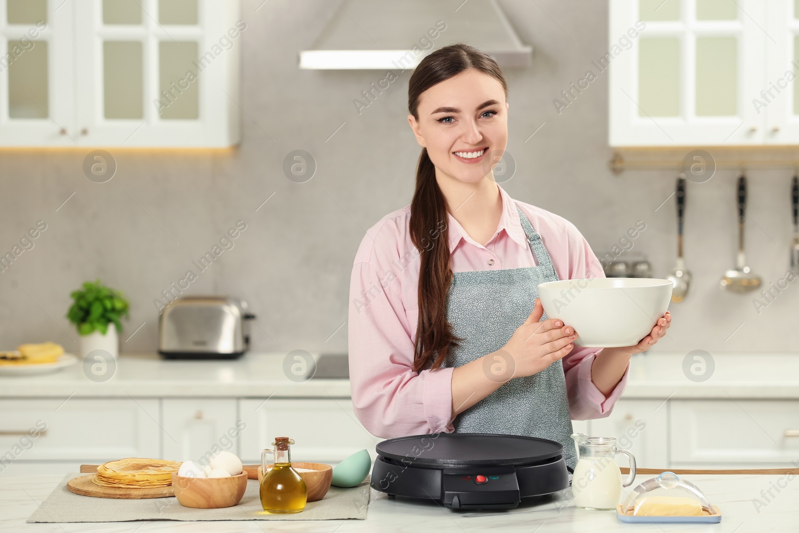 Photo of Happy woman with dough for crepes at white marble table in kitchen