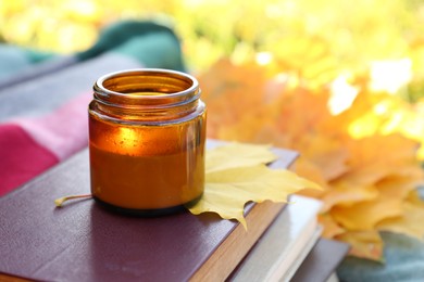Photo of Burning candle, books and dry leaves outdoors, closeup view with space for text. Autumn atmosphere