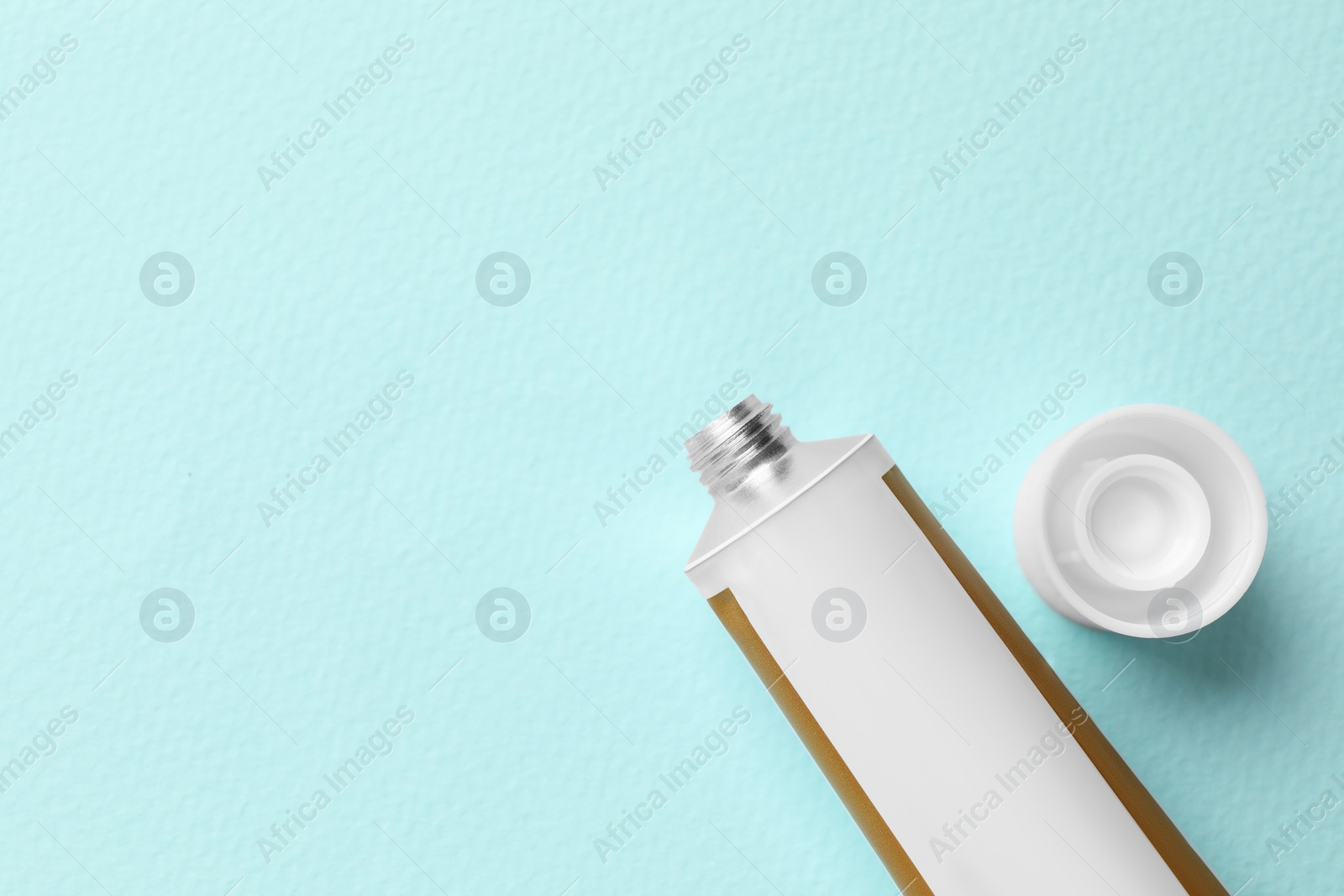 Photo of Open tube of ointment on light blue background, flat lay. Space for text
