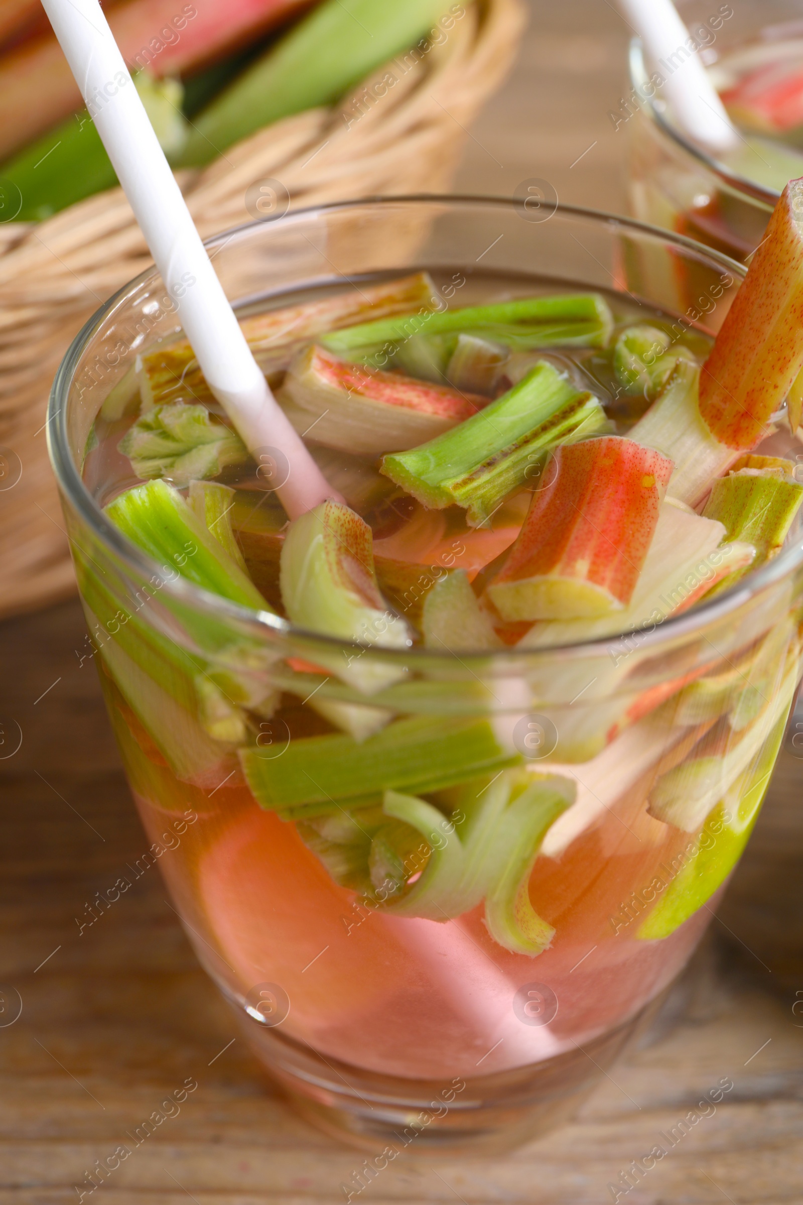 Photo of Glass of tasty rhubarb cocktail on wooden table, closeup