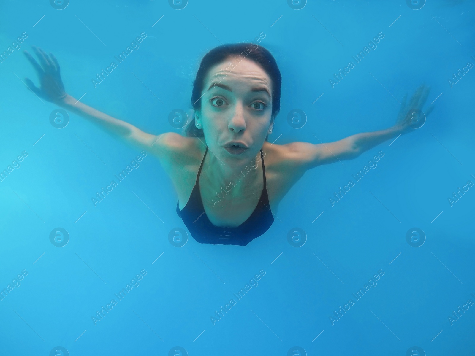 Photo of Beautiful young woman swimming in pool, underwater view