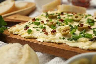 Photo of Fresh butter board with cut olives, onion and sun-dried tomatoes on table, closeup