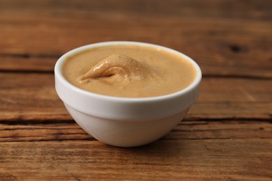 Delicious nut butter in bowl on wooden table, closeup