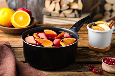 Delicious mulled wine and ingredients on wooden table