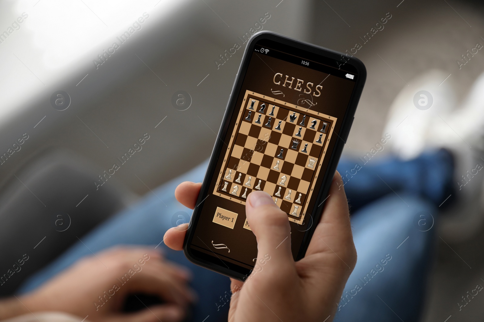 Image of Man playing online chess on smartphone indoors, closeup