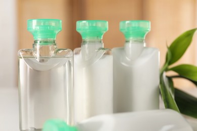 Photo of Mini bottles of cosmetic products on blurred background, closeup