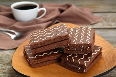 Photo of Tasty chocolate sponge cakes and hot drink on wooden table, closeup
