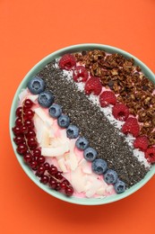 Photo of Tasty smoothie bowl with fresh berries and granola on orange background, top view