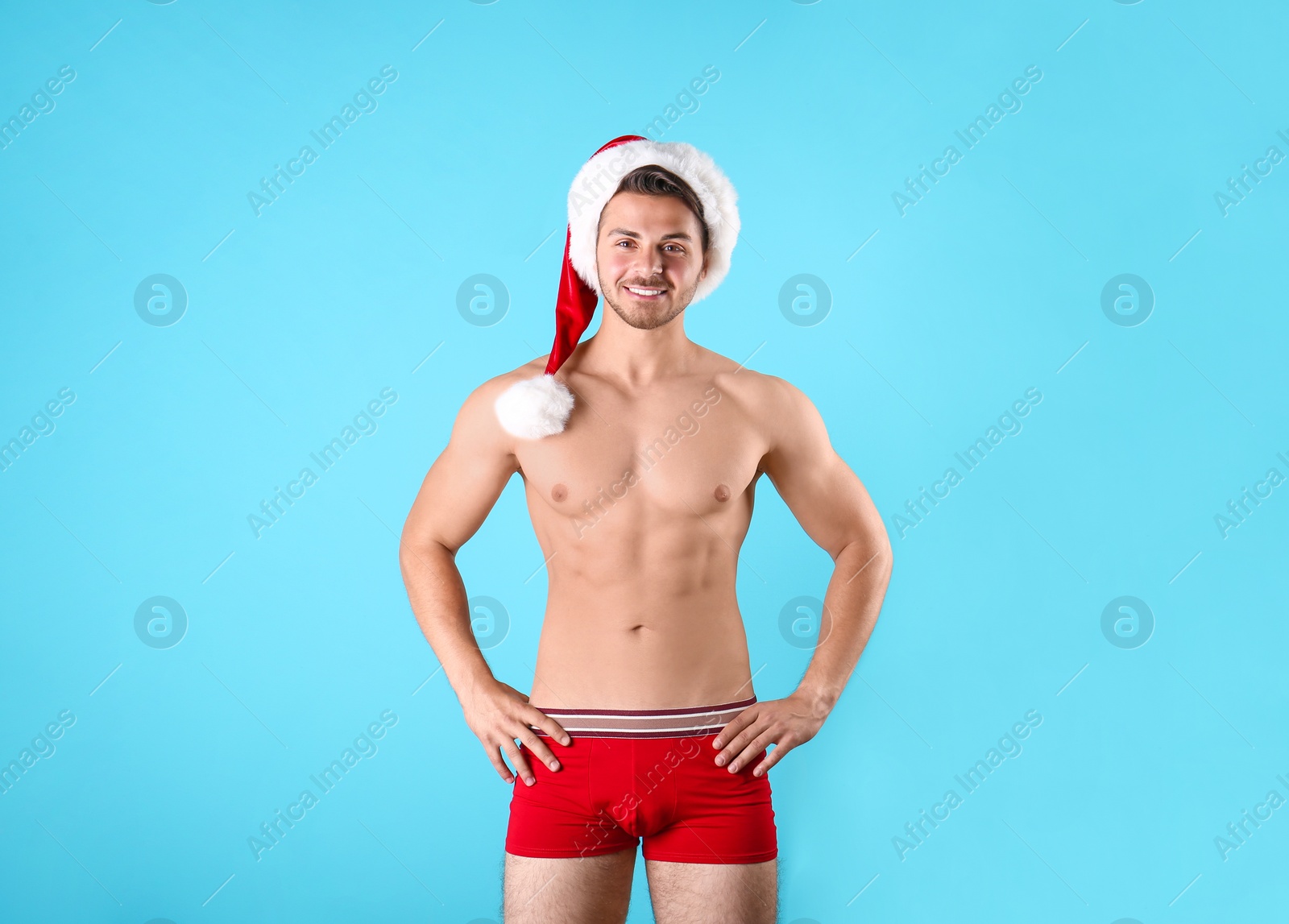 Photo of Shirtless young Santa Claus with sexy body on color background