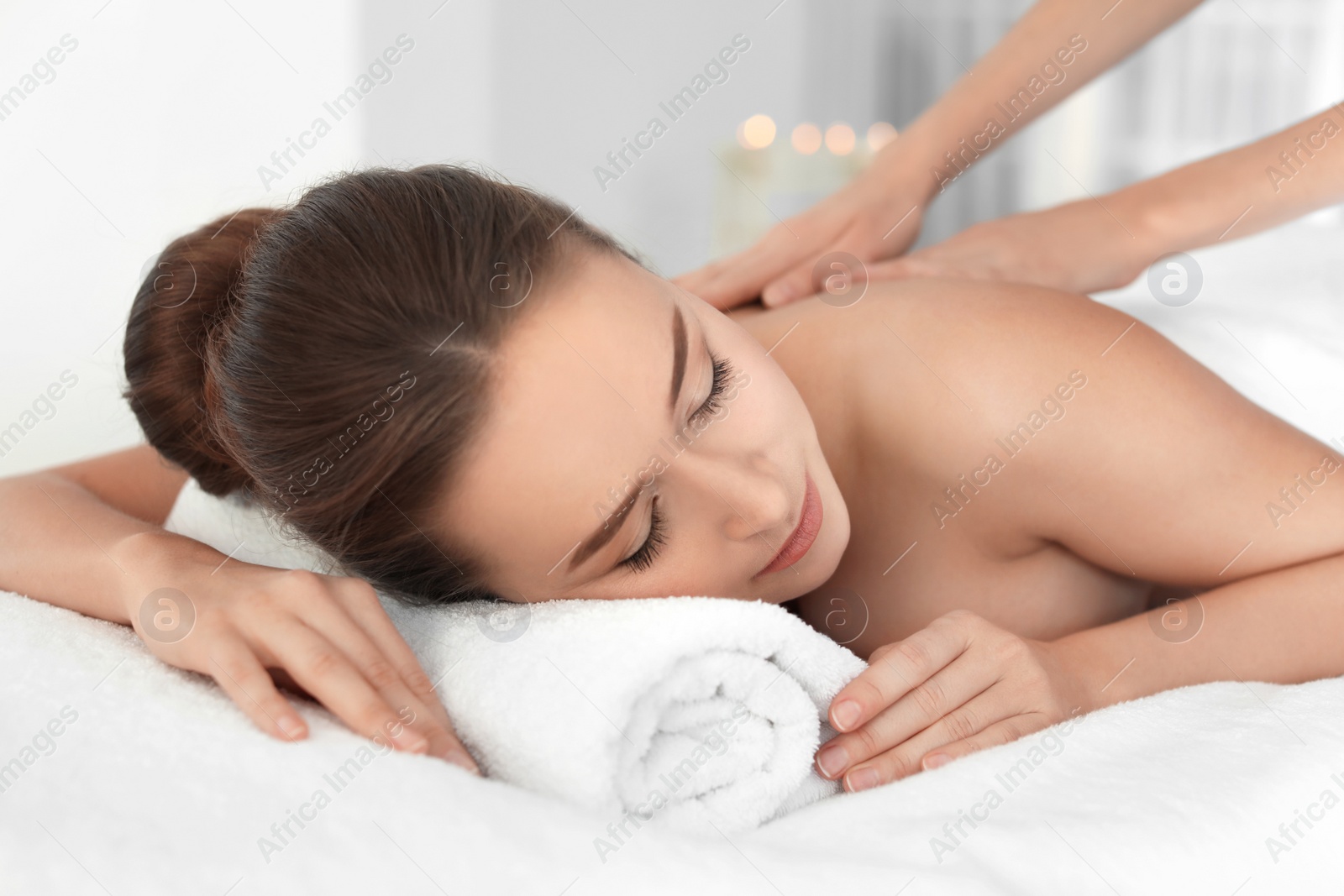 Photo of Young woman enjoying massage in spa salon