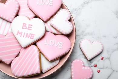 Decorated heart shaped cookies on white marble table, flat lay. Valentine's day treat