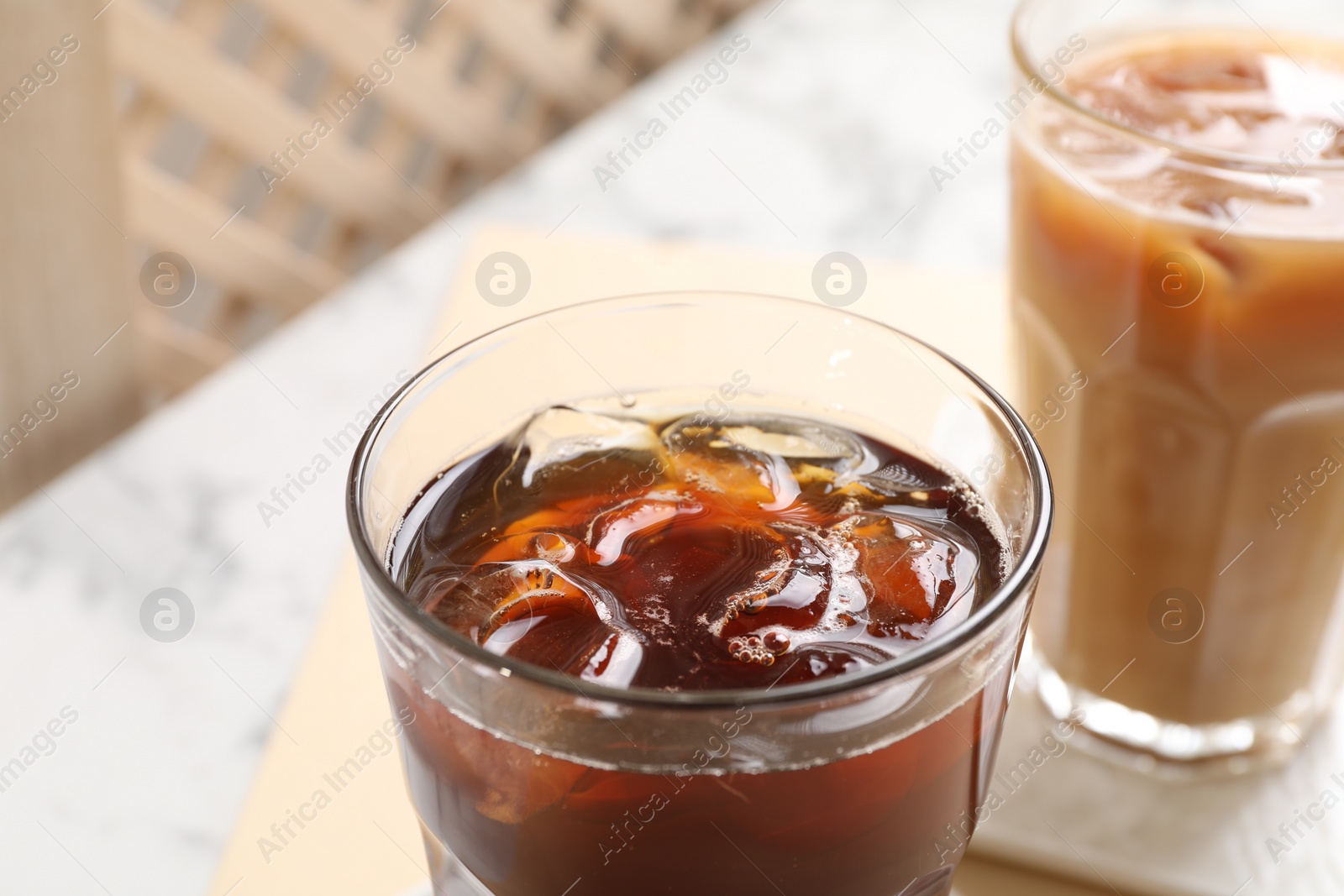 Photo of Refreshing iced coffee with milk in glasses on table, closeup